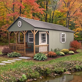 Olive green cabin shed with a porch set against autumn trees and a stream 